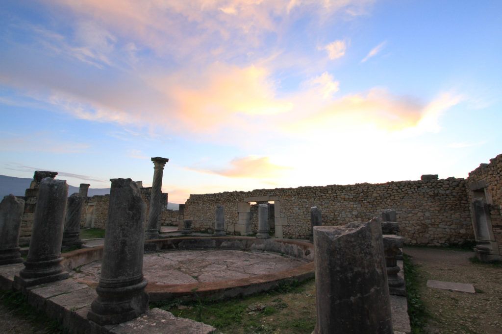 When visiting Volubilis, Morocco, plan to stay until dusk to experience the Roman ruins as the sun sets.