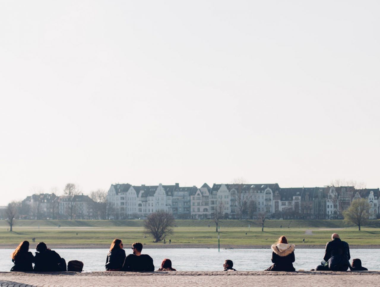 Many people on the Dusseldorf river bank enjoying the outdoors.