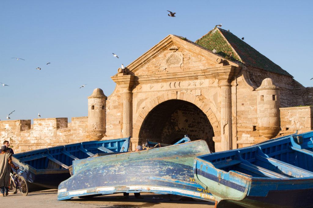 Blue fishing boats in front of Bab El Marsa, the gateway to Mogador Fortress in Essaouira.