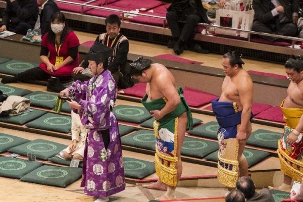 The referee leads the competitors into the auditorium.