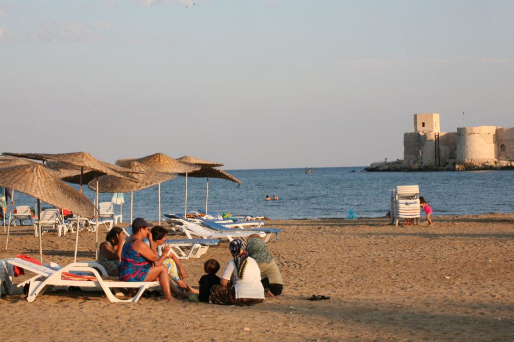 Ladies sitting on the beach looking out at the castle.