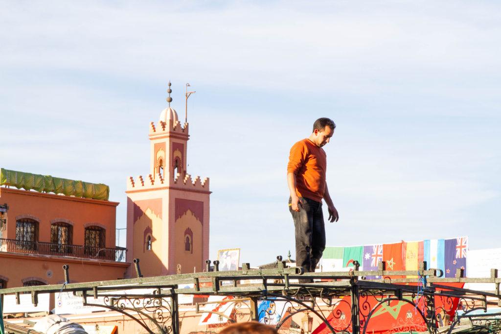 A man stands on top of the awning framework of a pop-up kitchen making sure it’s properly assembled.