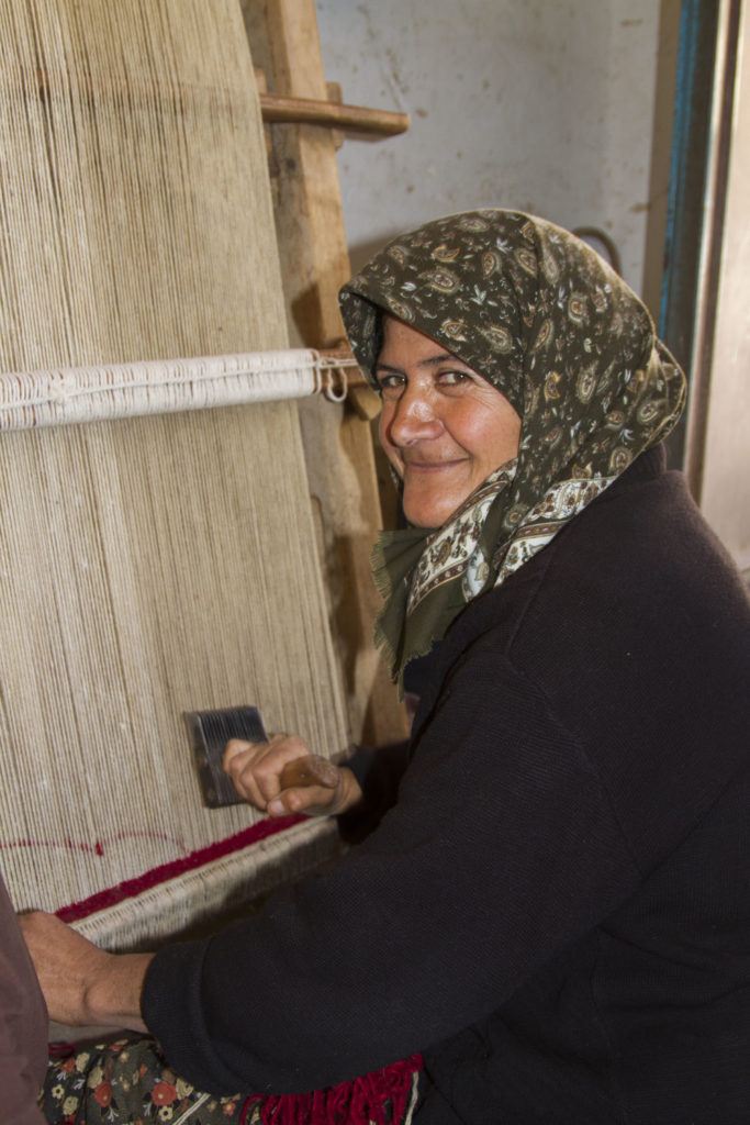 This village woman spends her days knotting rugs.