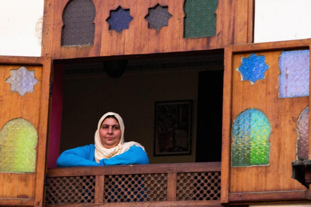 Overlooking the Fez souk, a woman looks out of a window at all of the activity.