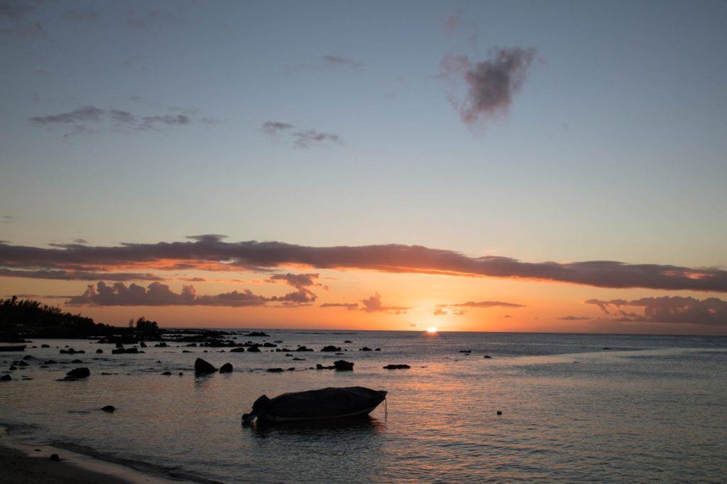 A silhouetted boat and rocks at sunset.