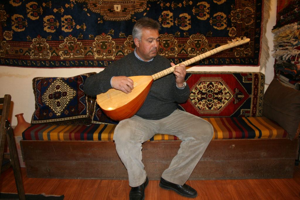 A rug merchant plays a Turkish stringed instrument called a saz or Baglama.