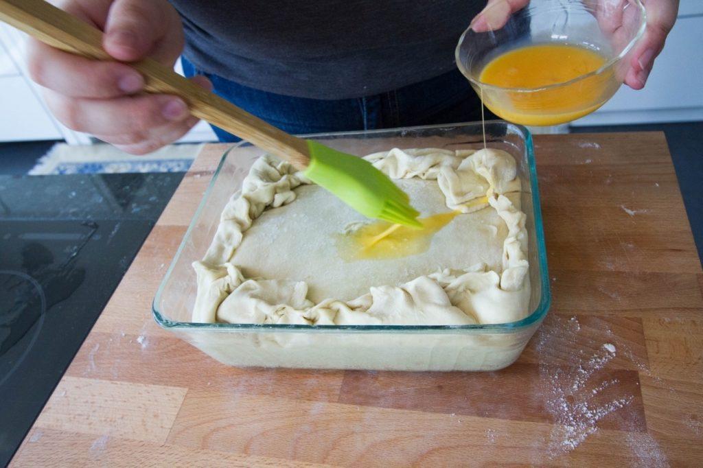 Brushing the pie with egg wash.