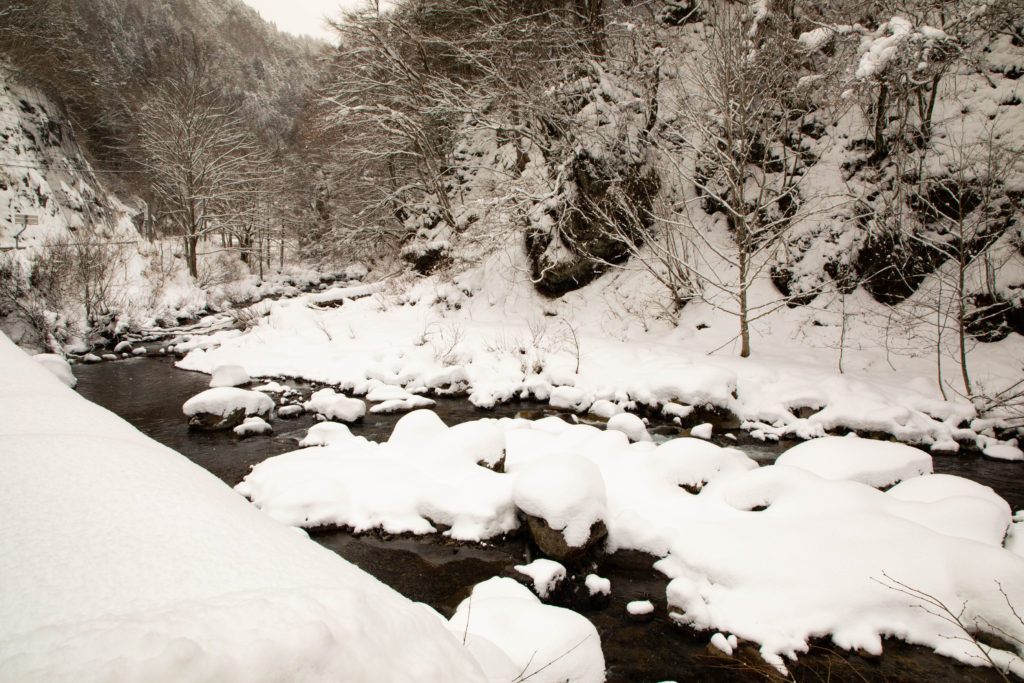 Snow piled high on the rocks in the Shiro River, Japan.