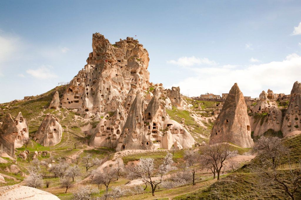 Cluster of cave houses on a beautiful spring day with grass turning green and trees starting to bloom.