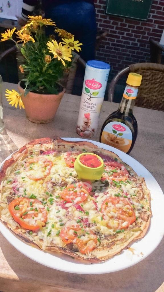 Dutch pancake with tomatoes, chives, onions, and beef alongside the powdered sugar and syrup.