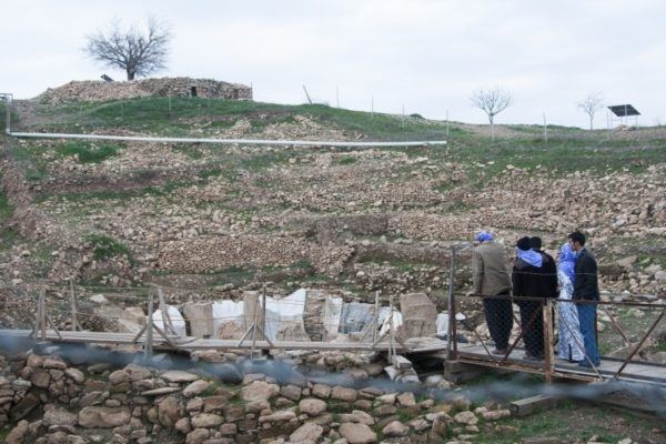 A small group stands on the platform overlooking Gobekli Tepe.