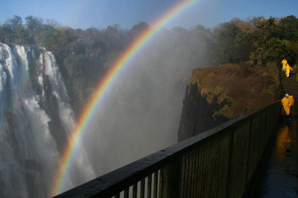 Victoria Fall Zambia is huge and wet, and people don yellow rain coats to stay dry.