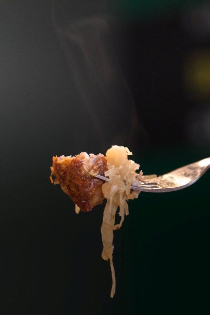 One bite of bratwurst with sauerkraut.