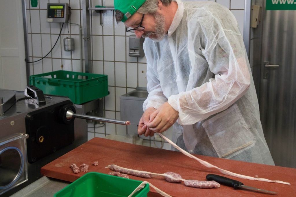 Jim putting the casing on the bratwurst as we learn how to make wurst. 