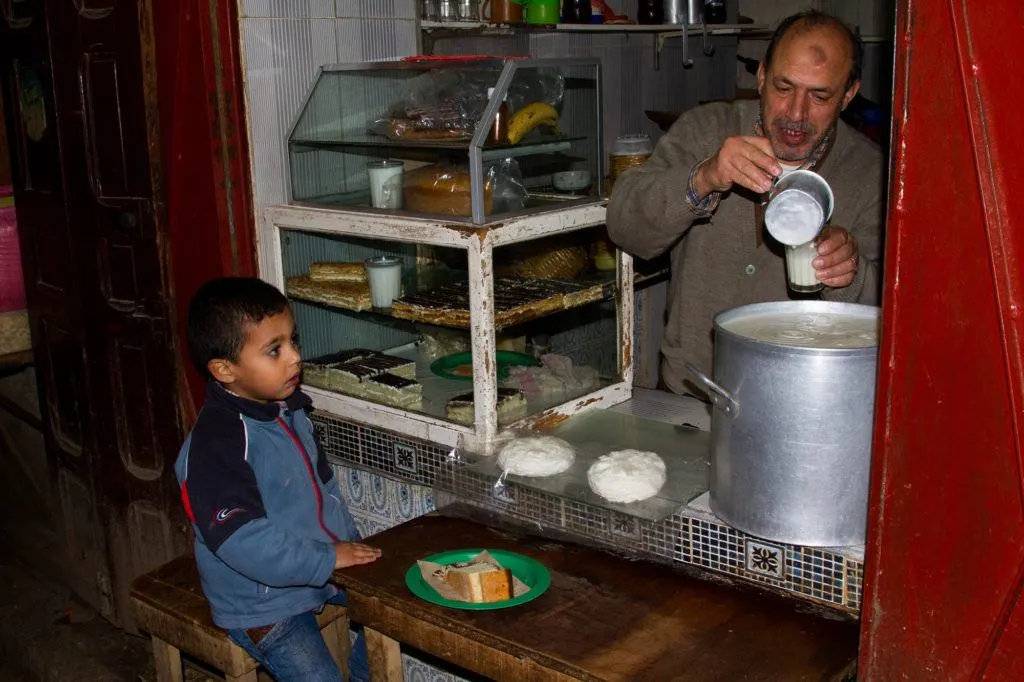 A young boy is served a snack at a small shop in the Fez Medina.
