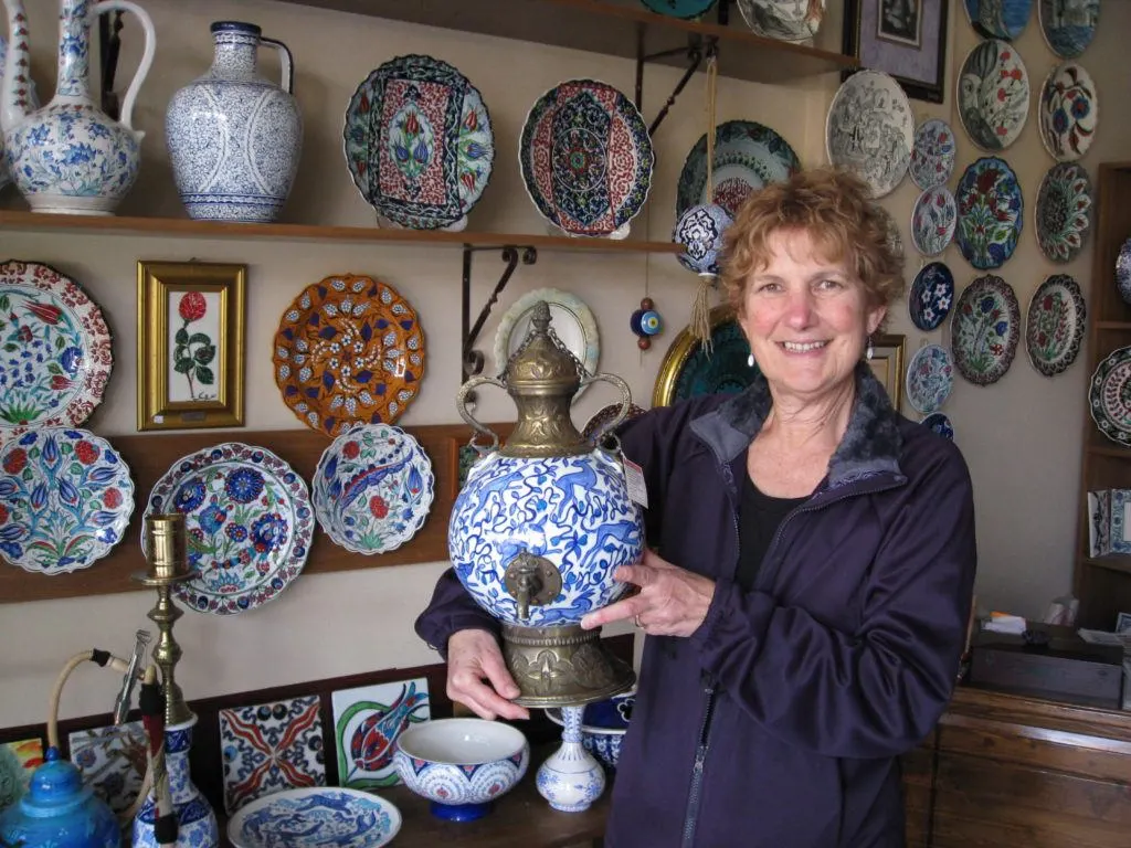 Women holding an Iznik-ceramic tea samovar in a Turkish ceramics shop.