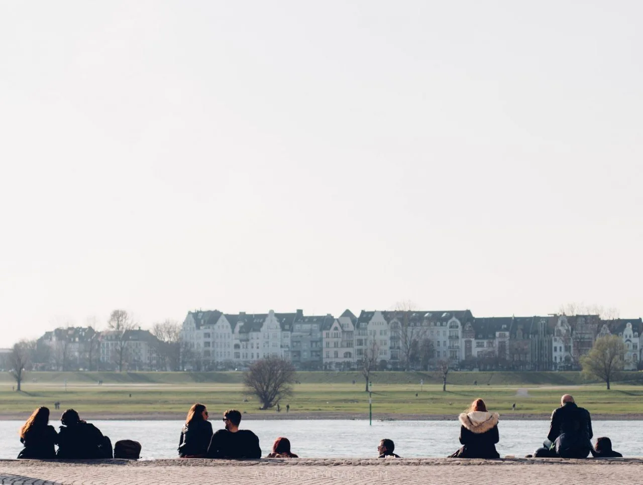 Many people on the Dusseldorf river bank enjoying the outdoors.