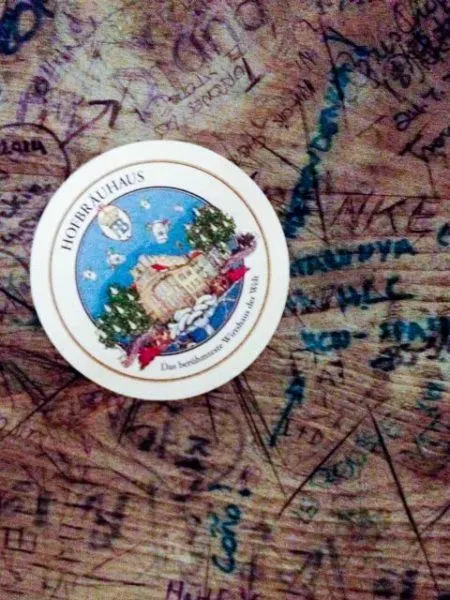 Hofbrauhaus table with grafitti and a coaster.