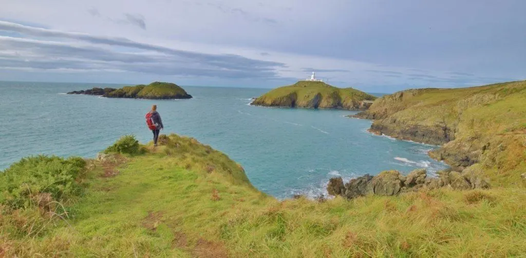 One hiker looks over the coast and at the water.