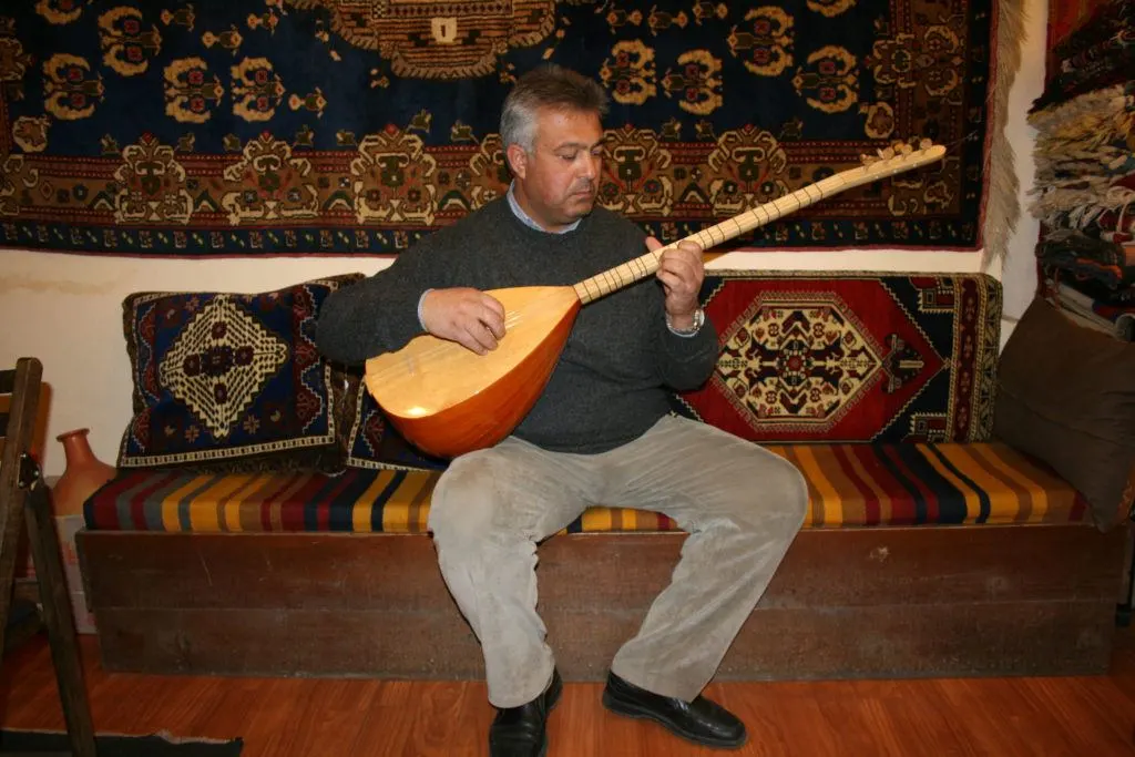A rug merchant plays a Turkish stringed instrument called a saz or Baglama.