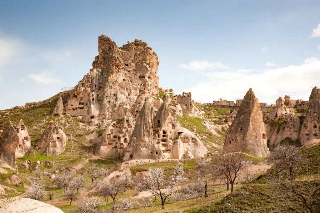 Cluster of cave houses on a beautiful spring day with grass turning green and trees starting to bloom.