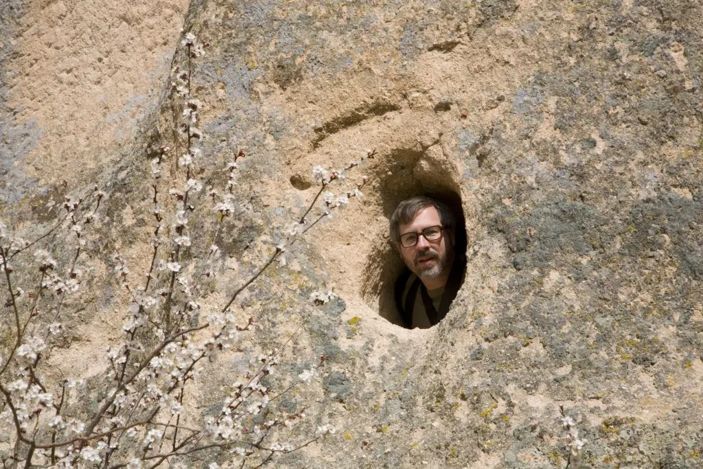 Jim peering out of a small opening in a rock cave.