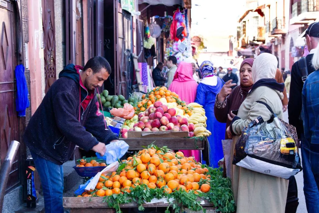 Women buying oranges from a fruit vendor in Marrakesh.